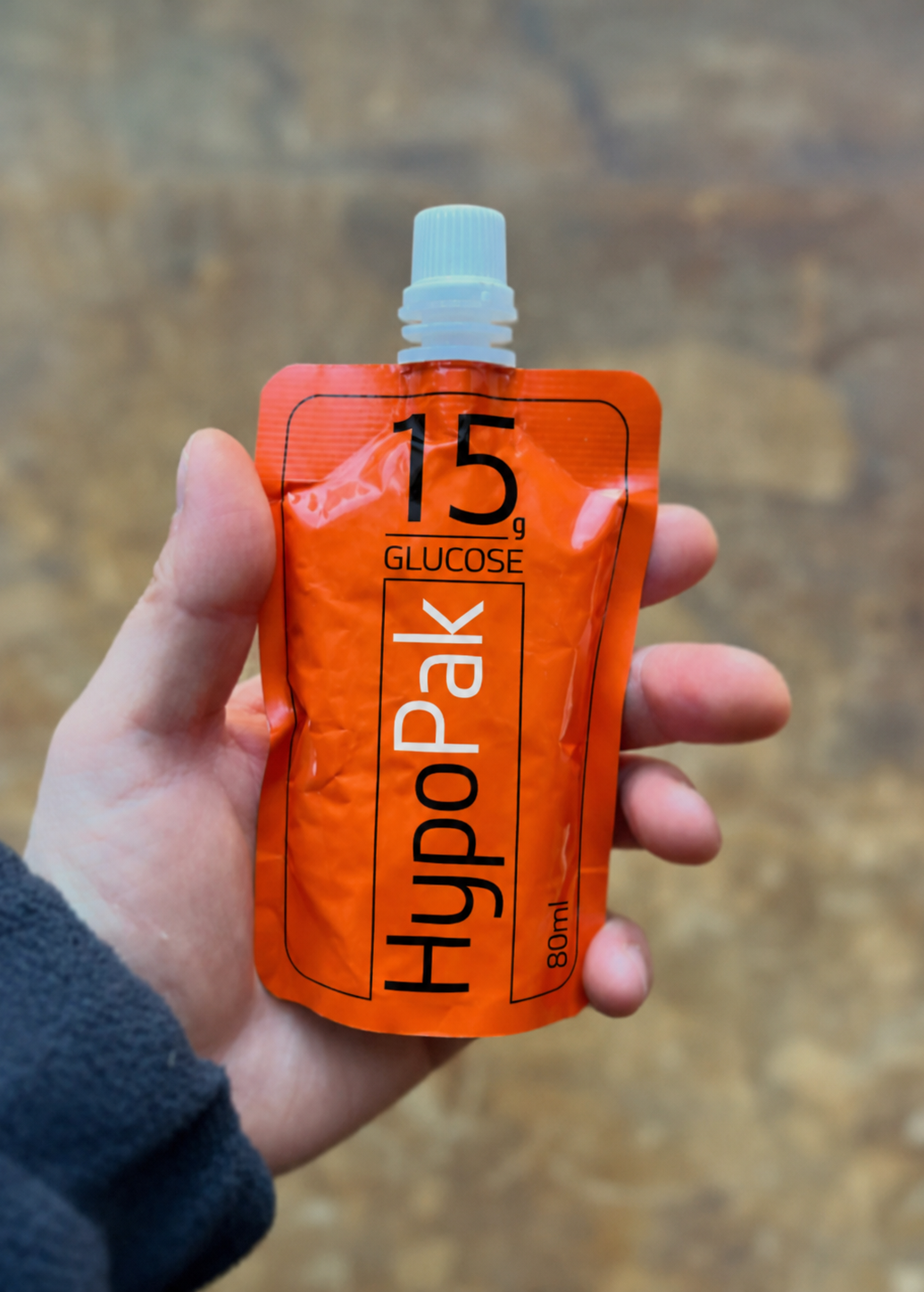Hand holding a HypoPak 15g glucose pouch